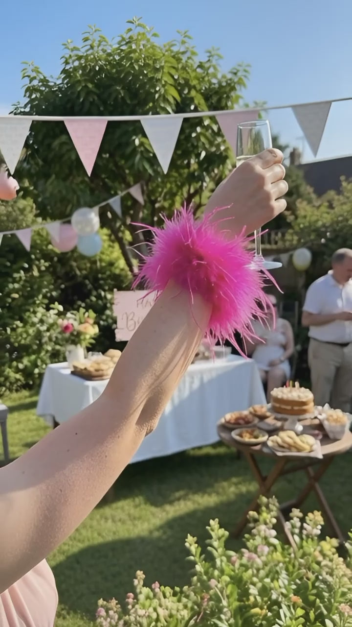 Video of a lady wearing a pink colored feather cuff at a sunny outdoors birthday party
