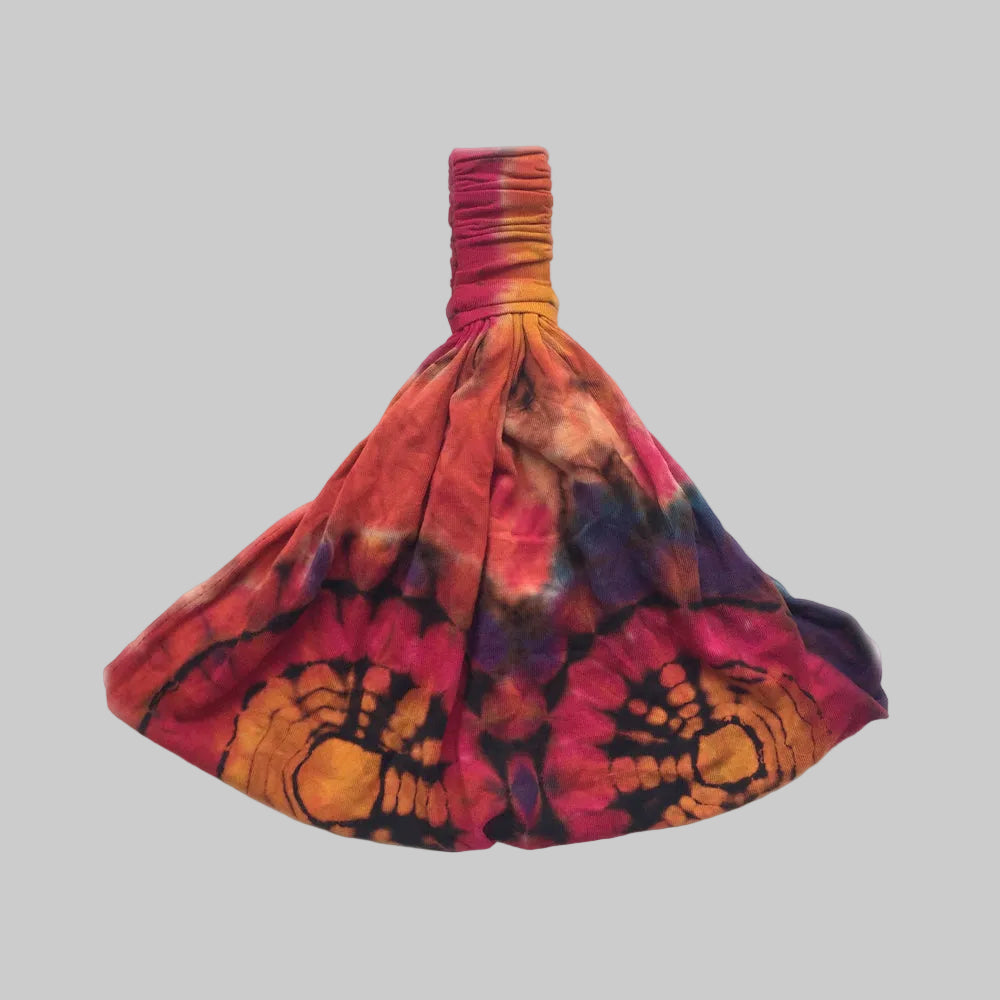 A tie-dye cotton stretchy jersey headband in a wide, hippie-style fashion, predominantly red and orange with a pattern.
